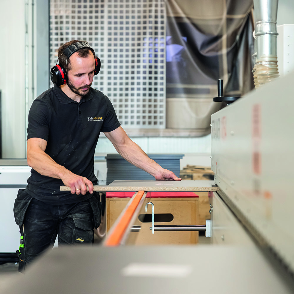 Meubelmaker bewerkt plaatmateriaal in de werkplaats van Vida Interieur