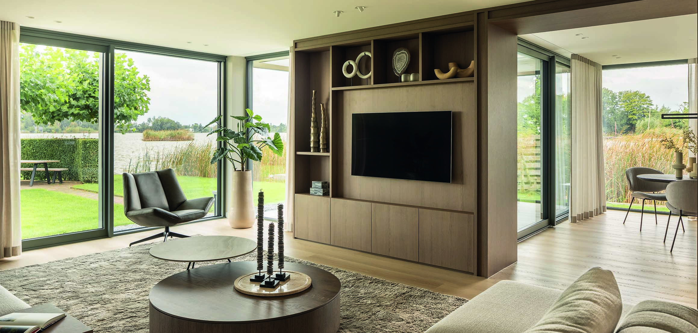 Woonkamer met maatwerk tv-wand en tuinzicht in Reeuwijk
