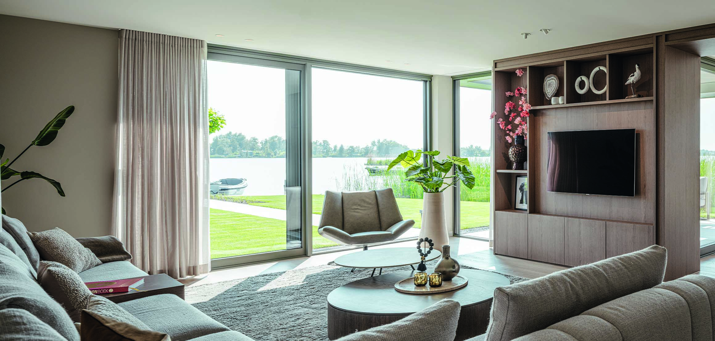 Woonkamer met tv-wand en uitzicht op de plassen in Reeuwijk