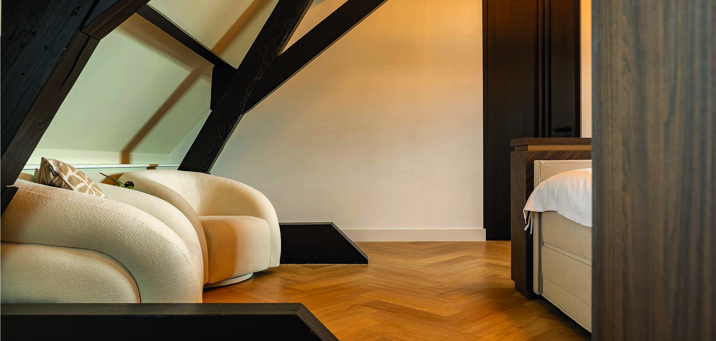 Zolder met fauteuil onder donkere spanten in Warmond
