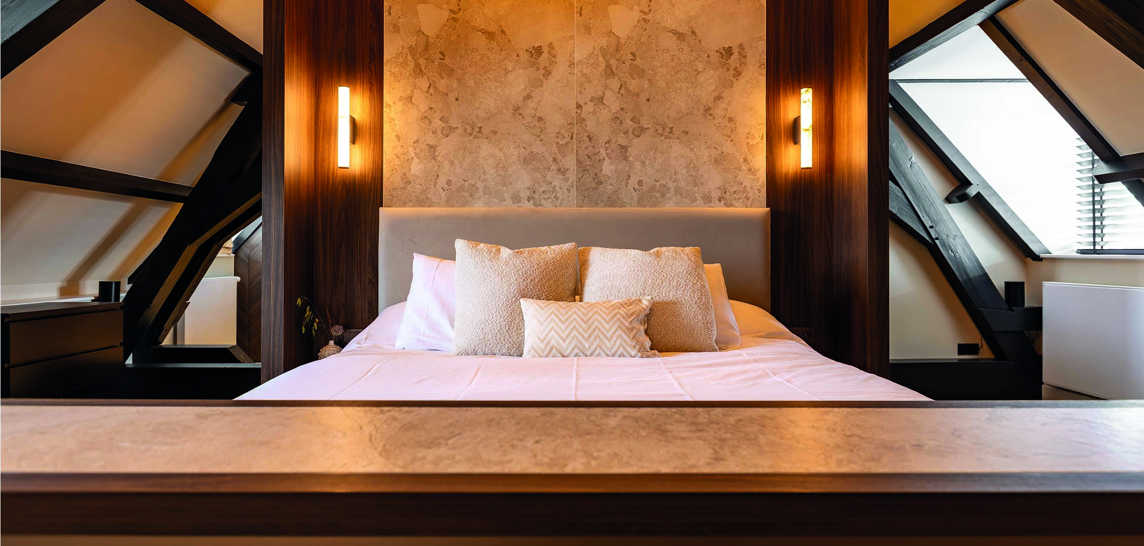 Bed met wandverlichting en natuurstenen wand in Warmond